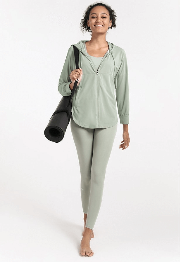 Woman in green quick dry hoodie with zipper and yoga mat, ready for fitness or yoga session.